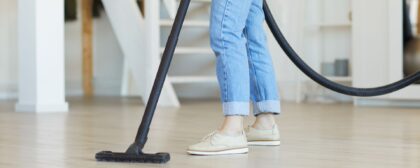 Close-up of woman vacuuming the dust from the floor at her house