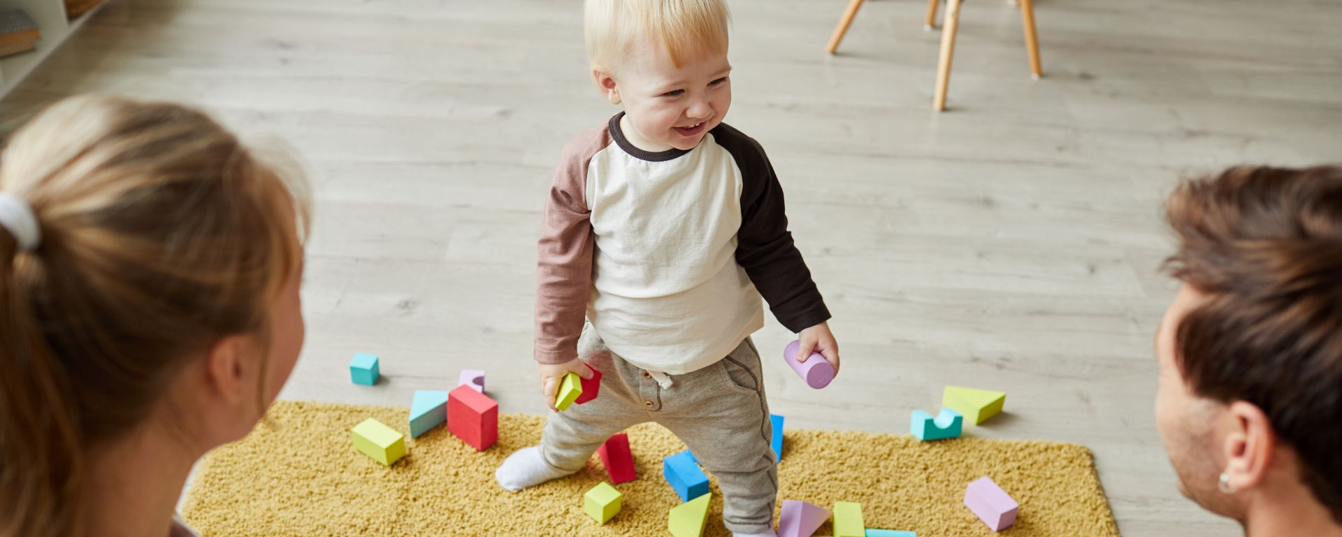 Child playing with toys on the floor together with his parents at home.