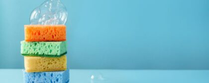 Stack of sponges with bubbles on top, in front of a blue background.