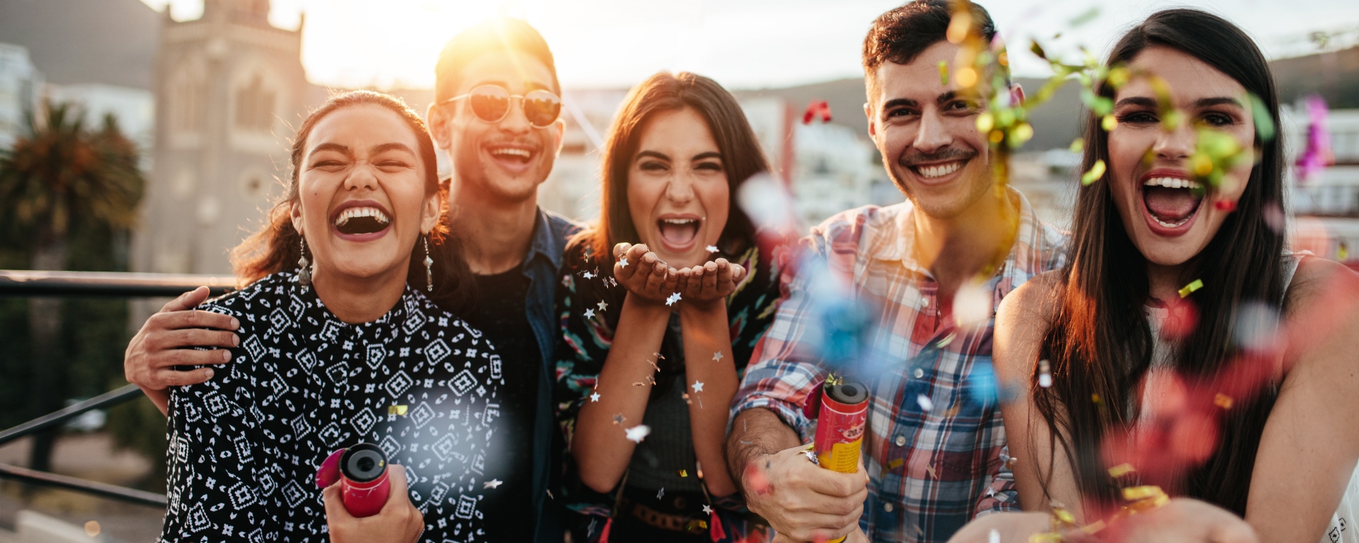 Friends celebrating outside together while popping confetti