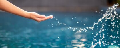 Close-up image of a hand splashing water in the pool