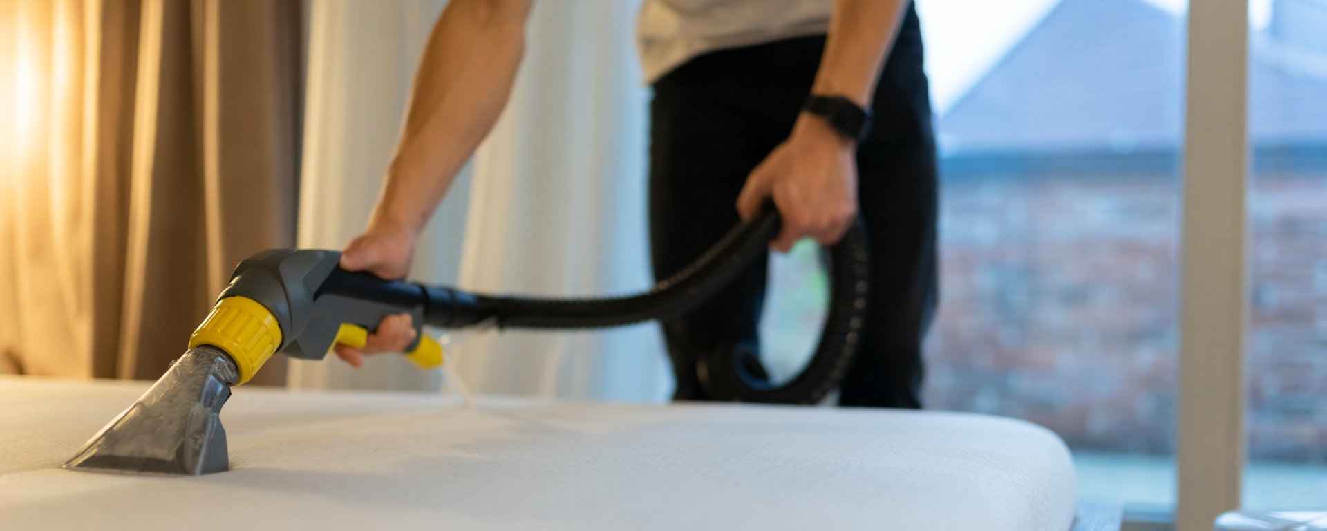 Close-up shot of a man vacuuming a mattress