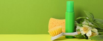 Flowers and cleaning tools in front of a green background. Spring cleaning concept.